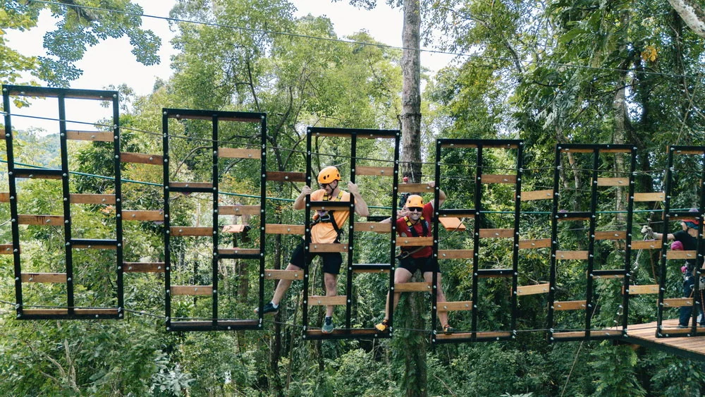 A helmeted participant moving across a suspended rope obstacle