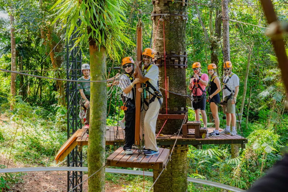 Helmeted visitors on a raised obstacle beside trees at Sky Rock